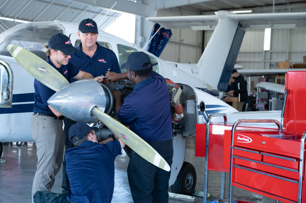 Team of Aviator College students working on a plane propellor.